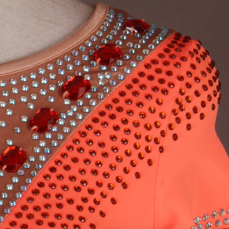 Close up of red and silver rhinestones on the orange ballroom dress neckline