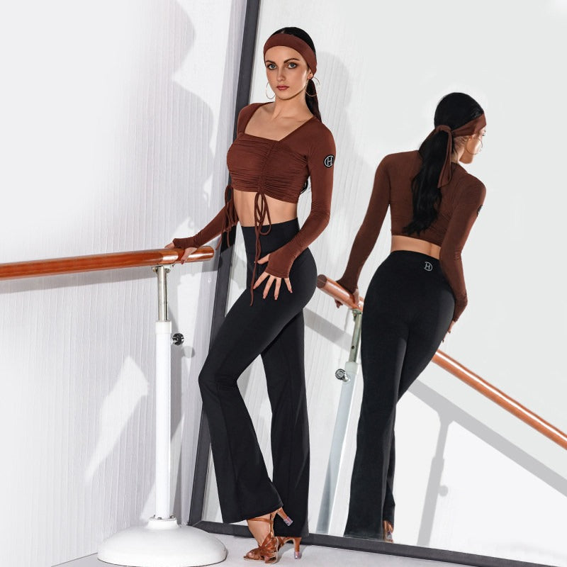 Black flared dancesport practice trousers worn at the barre