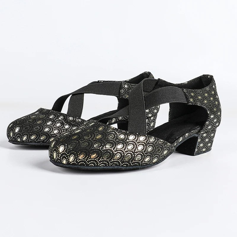 Black ballroom dance shoes pair with metallic gold peacock-eye print, closed round toe and crossed elastic straps on a low block heel