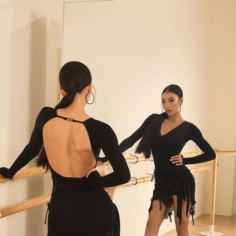 Black long sleeve open back leotard, back view styled with a fringe skirt