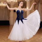 Navy ballroom dress worn by a dancer in a ballroom, full length front view