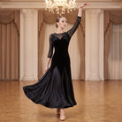 Black ballroom dress worn by a dancer in a ballroom, full length front view