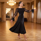 Dancer in a black ballroom practice dress with sparkle lace sleeves and a satin sash at the waist