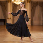 Black cold shoulder ballroom practice dress with sheer puff sleeves in a chandelier lit hall