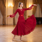 Wine red ballroom dress with a mesh yoke, lantern sleeves and satin sash turning in a ballroom