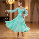 Mint green ballroom dance dress with sheer bishop sleeves and a satin waist bow in a ballroom