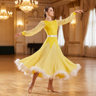 Yellow ballroom dance dress with a feather trimmed hem and sheer lantern sleeves mid turn