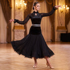 Black ballroom dance dress with a white sash at the waist and mesh peplum turning in a ballroom