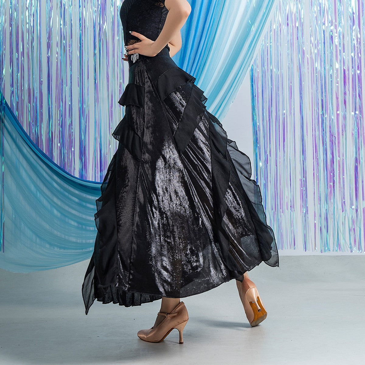 Black ballroom dance skirt with diagonal chiffon ruffle tiers, back view with hand on hip