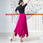 Fuchsia ballroom dance skirt with ruched hip yoke and pointed hem, back view at the barre