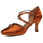 tan satin closed-toe ballroom dance shoe with crisscross ankle strap, rhinestone buckle, pleated toe