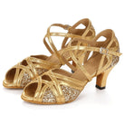 pair of gold latin dance shoes for women with metallic crossover straps over a glitter vamp and a low flared heel