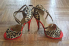 pair of leopard print samba platform dance heels for women with crossed ankle straps and a red platform sole
