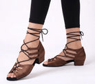 Woman wearing coffee brown satin lace-up open toe latin dance shoes with the laces tied above the ankle and a low block heel