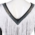 Close view of the studded V neckline above the white fringe